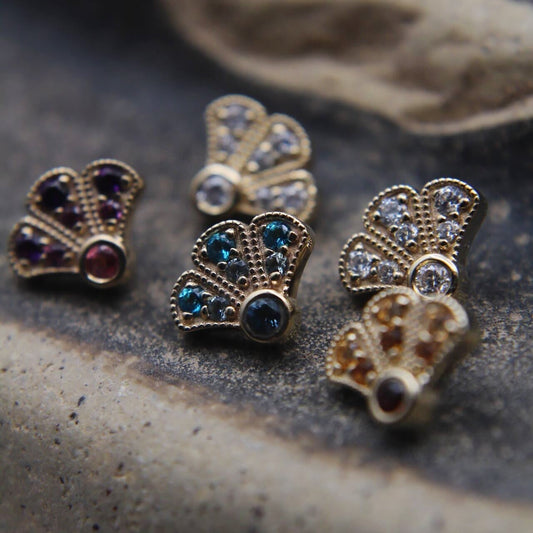 Gold earrings with gemstones on a textured surface