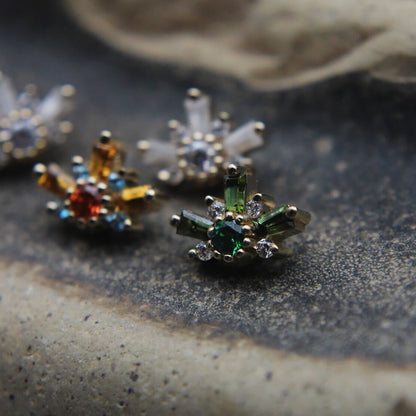 Close-up of decorative earrings on a textured surface featuring orange, green and clear stones