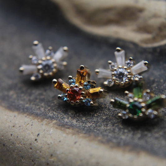 Close-up of decorative earrings on a textured surface featuring orange, green and clear stones