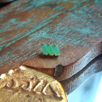 BVLA's "Liara" in 14k Yellow gold with 3 Chrysoprase shown on a background featuring a piece of wood with blue paint and a small golden piece on the bottom left side of the photo