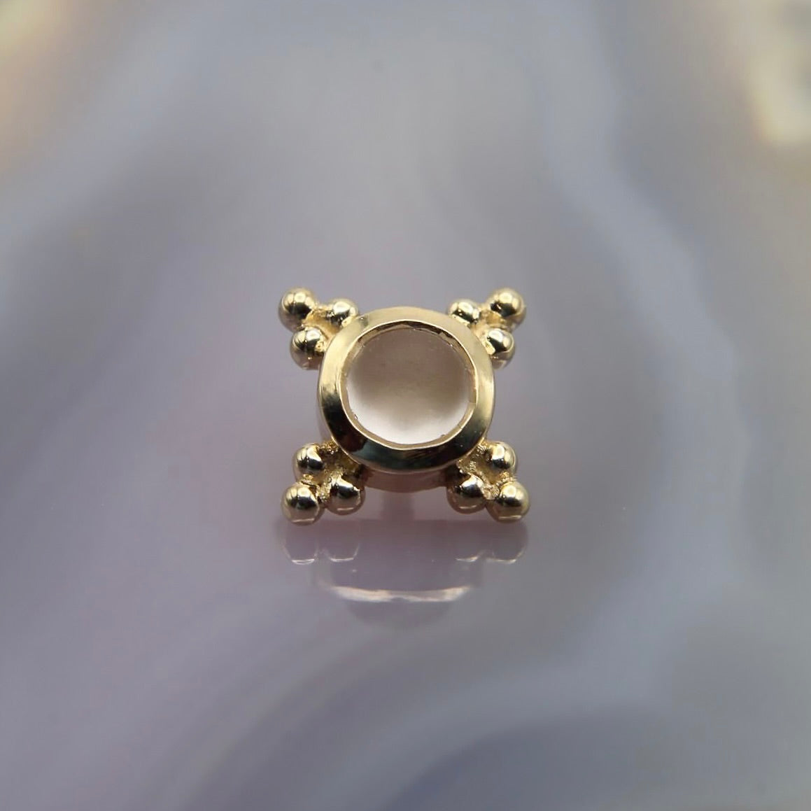 BVLA's "Mini Kandy" in 14k Yellow gold with a Sandblasted Rose Quartz laying on top of a purple background