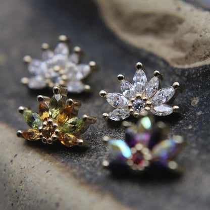 Four floral-themed earrings on a textured stone surface
