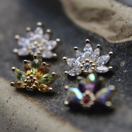 Four floral-themed earrings on a textured stone surface