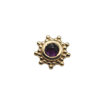 Gold sun-shaped stud with a central amethyst gemstone on a white background