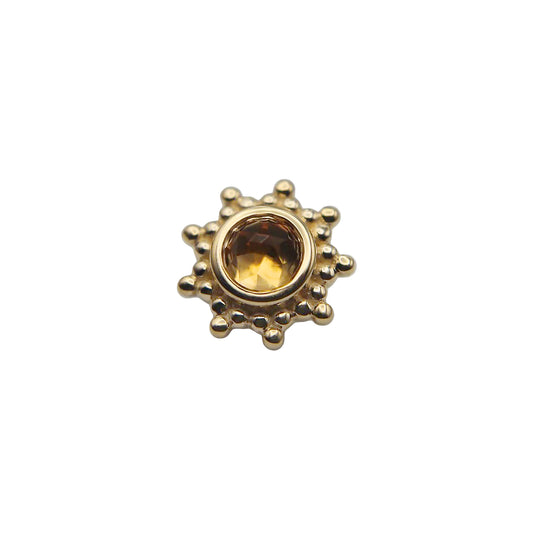Gold sun-shaped stud with a central citrine gemstone on a white background