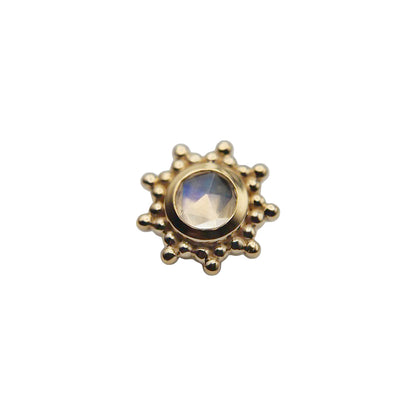 Gold sun-shaped stud with a central rainbow moonstone gemstone on a white background