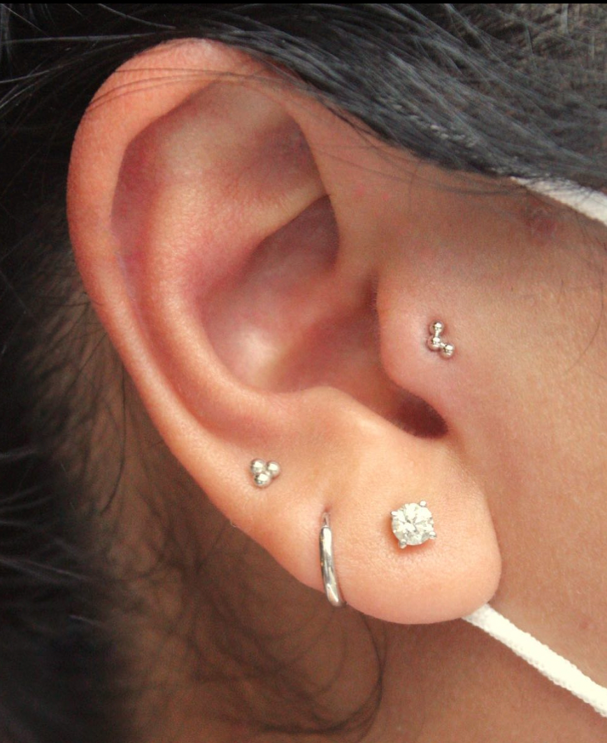 Right ear featuring a BVLA "Tri Bead Arc" in 14k White gold in a tragus piercing as well as other white gold jewelry