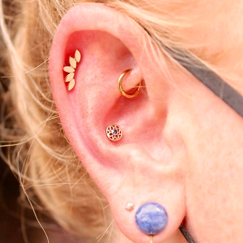
                  
                    Right ear featuring a BVLA "Flat Serenity" in 14k Yellow gold and an assortment of other yellow gold jewelry and a large purple stone in the first lobe piercing
                  
                