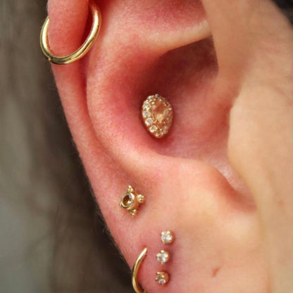 Right ear with an assortment of BVLA jewelry in 14k Yellow gold with CZ and Oregon Sunstone as well as two fitted 14k Yellow gold hoops