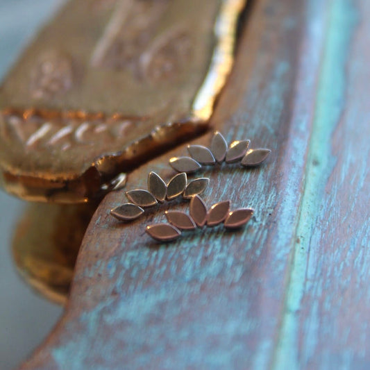 BVLA's "Flat Serenity" shown from top to bottom in 14k White gold, 14k Yellow gold and 14k Rose gold. Shown on a background featuring a piece of wood with blue paint on bottom and a small golden piece on the top left of the photo