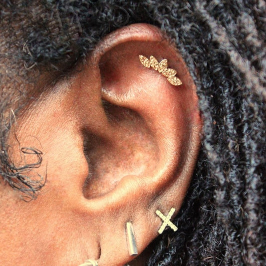 Left ear featuring BVLA's "Hammered Serenity" in 14k Yellow gold in a helix piercings. Client's personal gold jewelry in 3 lobe piercings